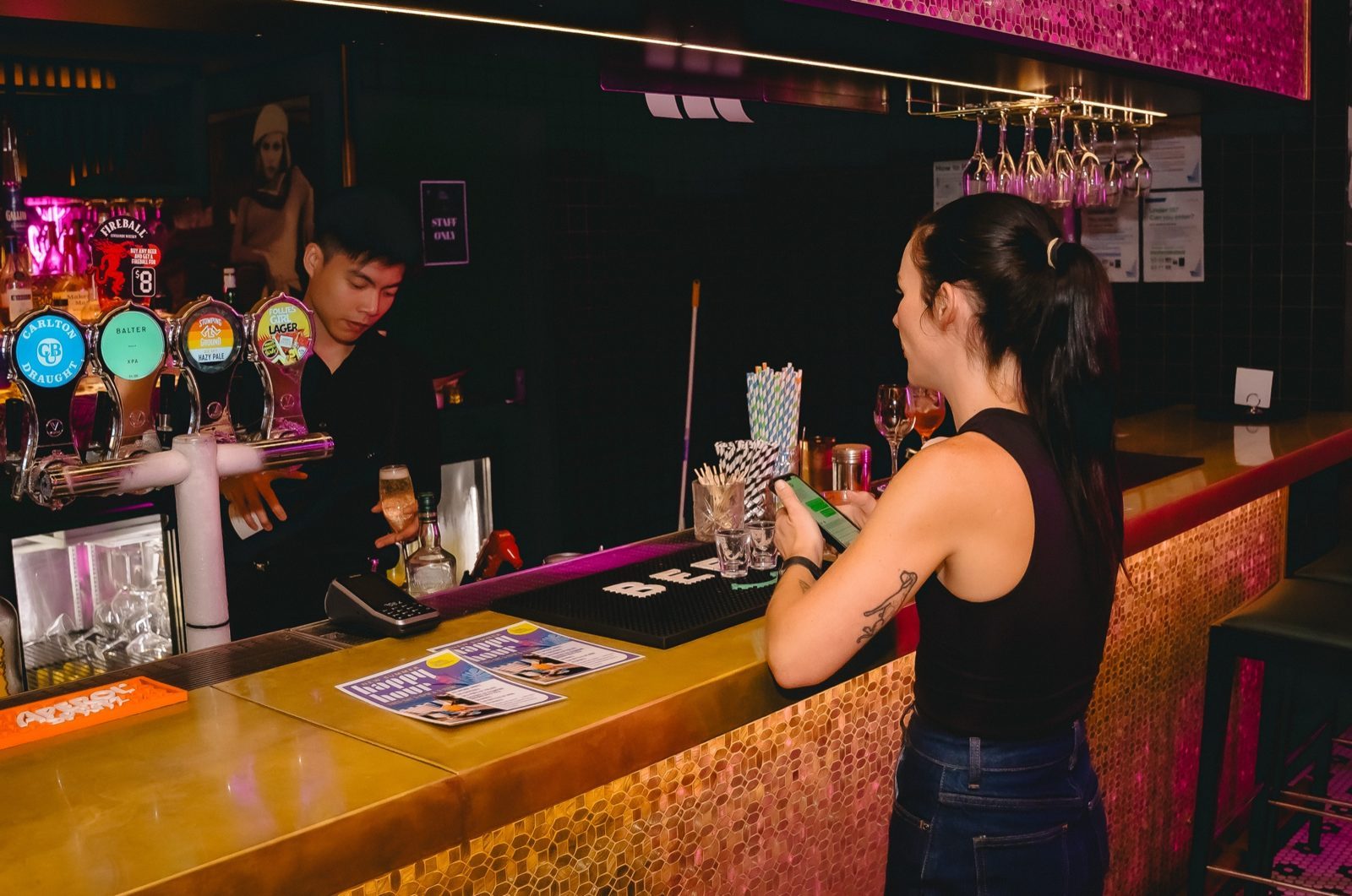 Guest leaning on the gold-tiled Follies bar with a cocktail
